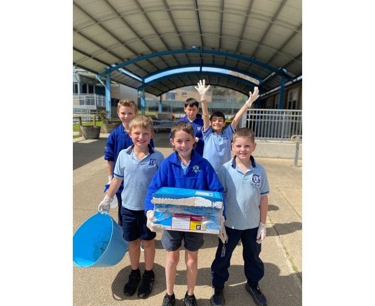 Group of boys from the schools garden club. Boy in front holding a box which they are growing mushrooms in.